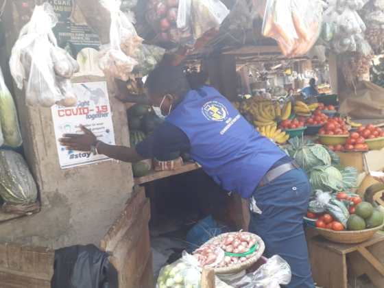Blog 7 Henry pinning up posters in the market